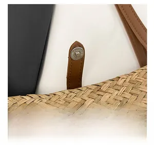 Macro view of woven straw tote bag featuring leather strap and magnetic metal clasp closure