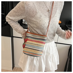 Detailansicht der gewebten Stroh-Eimertasche mit bunten Regenbogenstreifen und Erdbeeren