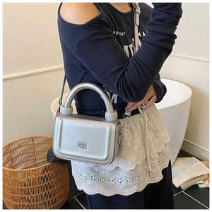 Close-up of silver lychee grain leather handbag with thick handle and metallic clasp detail