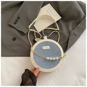 Détail du sac rond brodé avec texture tissée, perles et étiquette de la marque