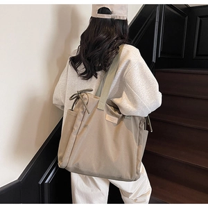 Rear view of khaki canvas tote bag with drawstring details on casual streetwear model