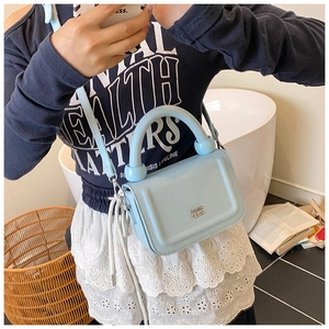 Detail of light blue lychee pattern leather bag with silver logo and round handle