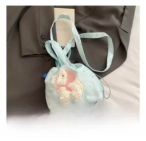Dettaglio borsa a secchiello azzurra a pois bianchi con toppa di animale in peluche