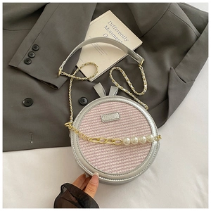 Détail du petit sac rond rose tissé avec bandoulière en chaîne dorée et perles