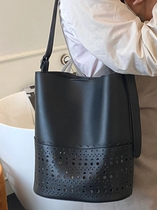 Elegant black leather bucket bag with laser-cut hollow patterns and matching shoulder strap