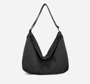 Détail du sac hobo en jean noir montrant la texture du tissu et la bandoulière réglable