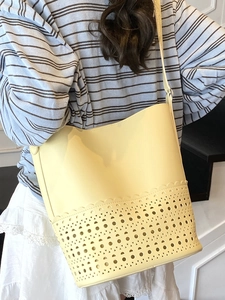 Light yellow hollow out bucket bag with geometric laser cut pattern and wavy edge