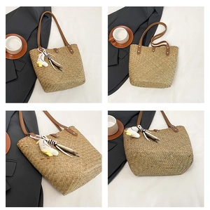 Detail view of handmade straw tote bag with leather straps and plush bird pendant