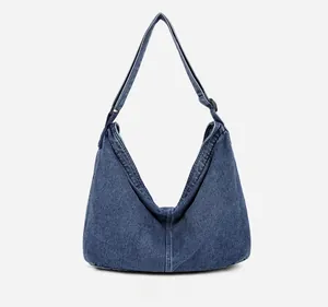 Détail du tissu denim délavé et de la bandoulière réglable du sac hobo rétro