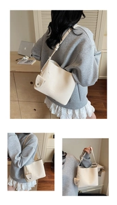 Detail showing the creamy beige lychee grain leather texture and round charm on the bucket bag