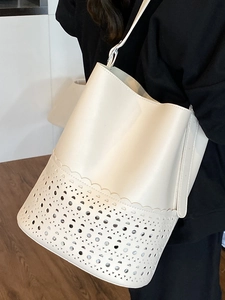 Chic white cutout bucket bag featuring geometric laser-cut patterns for summer style