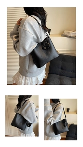 Detail view of a black lychee texture bucket bag on a model in a warm home setting