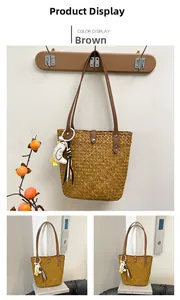 Detailed close-up of brown straw tote bag with leather strap and cute duck charm accessory