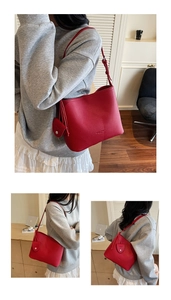 Close-up of red lychee pattern leather bucket bag with heart charm and adjustable strap