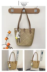 Detail view of woven straw tote bag with brown leather straps and cute bird charm