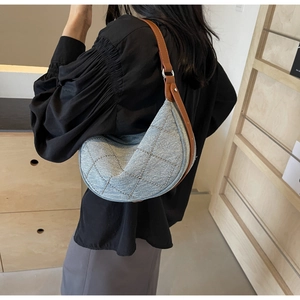 Dettaglio borsa a mezzaluna in denim azzurro con borchie argento e tracolla in pelle marrone