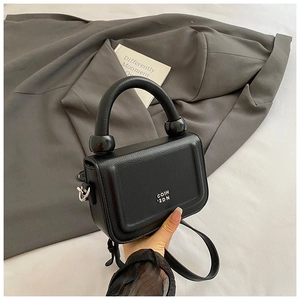 Detail of black pebbled leather mini bag with unique sphere handle and chain strap