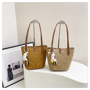 Detail of woven straw tote bags with faux leather handles and cute chicken charms