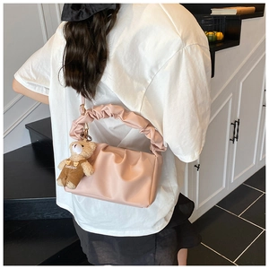 Detailed view of a pink pleated cloud bag with a cute teddy bear charm on the strap