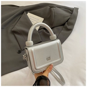 Detailed macro of silver textured leather handbag with metallic finish and brand logo