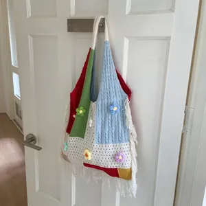Detail of colorful crochet tote bag with 3D floral accents and white fringe tassels