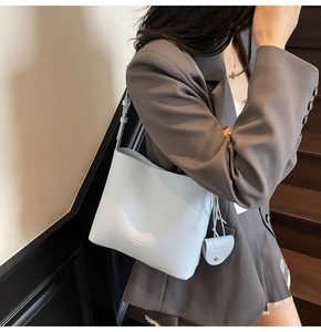 Close-up of light blue leather bucket bag with matching strap on a model outfit