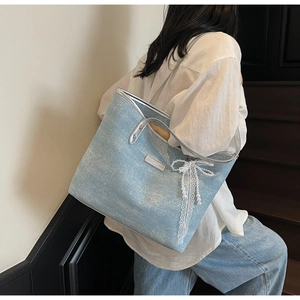 Detail of light blue denim tote with silver metallic piping and lace bow with pearls