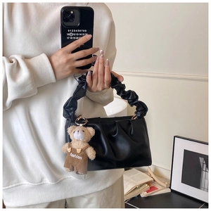 Detail of black pleated cloud bag with stylish teddy bear charm and soft handle