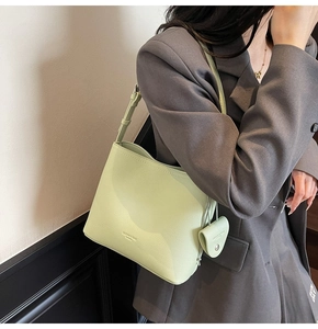 Detail view of light green bucket bag with lychee texture and heart charm accessory