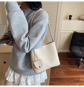 Detail of off-white lychee leather bucket bag featuring a mini coin purse and brand stamp