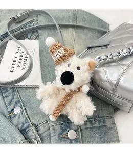 Close-up of white plush puppy charm with Lovely knit hat and scarf on a quilted bag