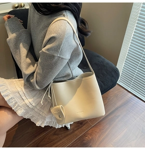 Detail of creamy white pebble leather bucket bag showing fine texture and brand logo