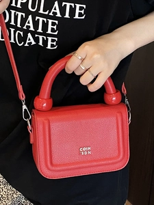 Modern red pebbled leather underarm bag with thick cylindrical handle and silver logo