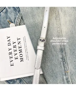 Close-up of adjustable silver metallic chain strap with buckle on denim fabric
