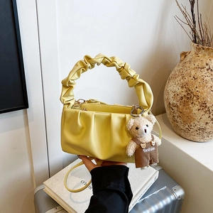 Close-up of pleated cloud-shaped handbag in yellow leather with cute bear charm detail