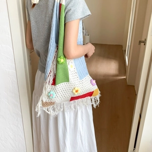 Detail view of handmade crochet tote bag with colorful 3D flowers and long fringe tassels