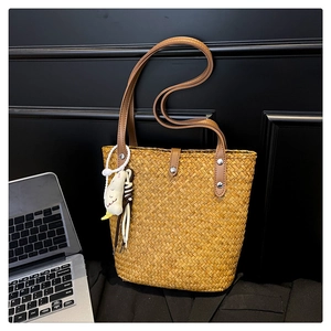 Detail of straw tote bag with brown PU leather trim and a cute duck plush charm