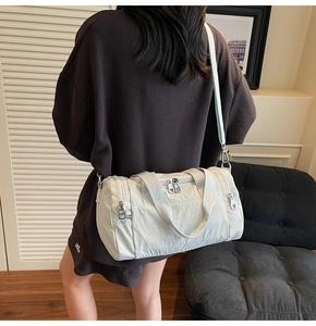 On-body view of a cream cylinder sports bag showing its size and adjustable shoulder strap