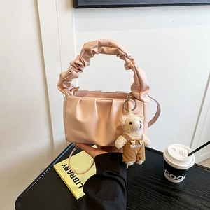 Detail of pink pleated cloud bag with stylish teddy bear charm and ruffled handle strap