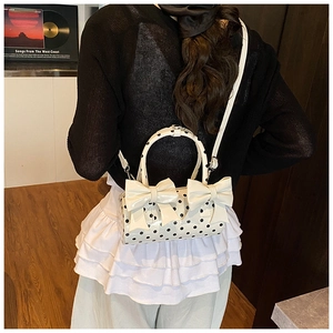Vue détaillée du sac polochon blanc à pois avec deux nœuds noirs et une bandoulière