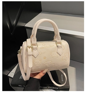 Close-up of cream Boston bag with embossed bear pattern and adjustable shoulder strap