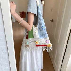 Detail of colorful knit tote bag featuring crochet flowers and long tassel fringe