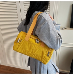 Detail of yellow nylon crossbody bag with multiple zippers and wide fabric strap