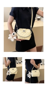 Detail view of cream quilted crossbody bag with silver twist lock and plush puppy charm