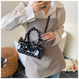 Sac cylindrique à pois noirs avec nœuds 3D présenté dans un décor d'intérieur
