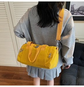Detail of a bright yellow nylon fitness bag with dual zippers and silver metal buckles