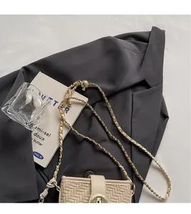 Détail du sac tressé beige avec fermoir rotatif doré et bandoulière en chaîne métal