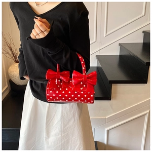 Détail du sac cylindre rouge à pois avec grands nœuds porté par un mannequin en escalier