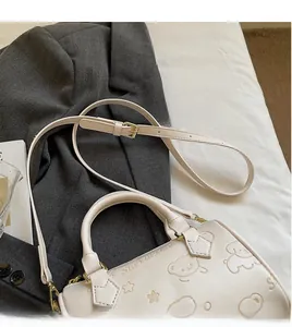 Close-up of beige Boston bag featuring embossed cartoon bear patterns and gold hardware