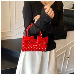 Détail du sac à main en cuir verni rouge à pois blancs avec deux nœuds élégants